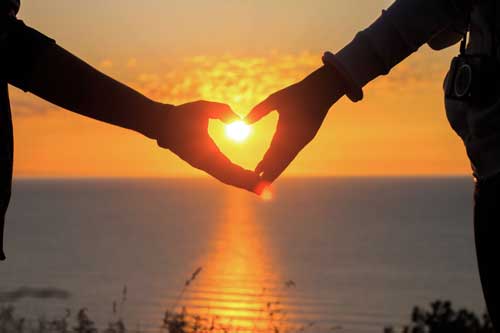 دستانی که در غروب خورشید قلب درست کرده اند